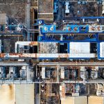 Vista aérea de uma instalação industrial moderna, com galpões e equipamentos, durante o dia.